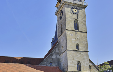 Stiftskirche Öhringen mit beschäftigtem Marktplatz, mit Personen die unter Schattenschirmen sitzen und essen | © Touristikgemeinschaft Hohenlohe e.V. | Andi Schmid
