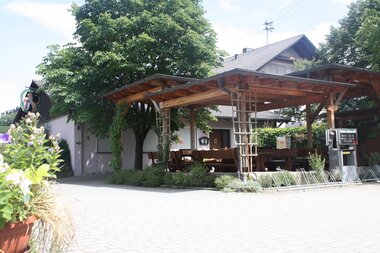 Eine überdachte Terrasse mit Bäumen vor dem Gasthaus | © Touristikgemeinschaft Hohenlohe e. V. | Gasthaus Löwen