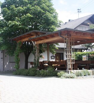Eine überdachte Terrasse mit Bäumen vor dem Gasthaus | © Touristikgemeinschaft Hohenlohe e. V. | Gasthaus Löwen