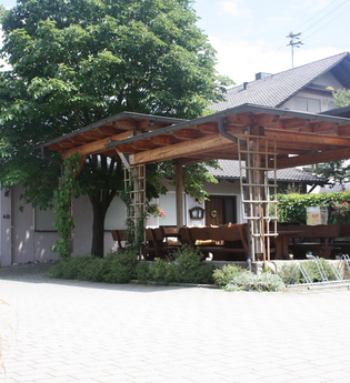 Eine überdachte Terrasse mit Bäumen vor dem Gasthaus | © Touristikgemeinschaft Hohenlohe e. V. | Gasthaus Löwen