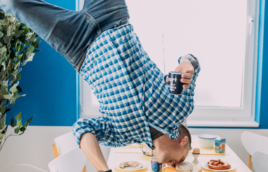 Blick in das Toppels "Haus auf dem Kopf". Es sieht so aus, als würde ein Mann mit dem Kopf nach unten über dem Tisch schweben und mit dem Mund vom Vesperbrettchen das Essen naschen. | © TOPPELS - Verdrehte Welt
