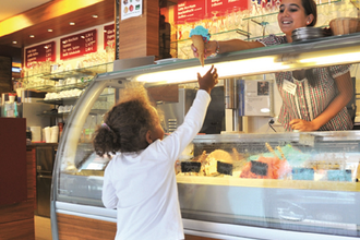 Eine Frau reicht einem Kind ein Eis übe die Theke | © Touristikgemeinschaft Hohenlohe e. V. | Bäcker Trunk