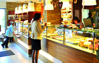 eine Frau steht vor einer Theke und wird bedient | © Touristikgemeinschaft Hohenlohe e. V. | Bäckerei Trunk