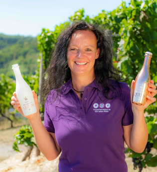 Ute Schmidt mit Lächeln im Weinberg mit 2 Flaschen in der Hand | © Ute Schmidt