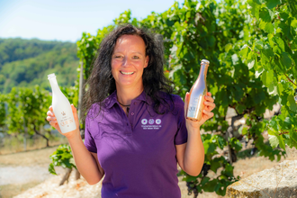 Ute Schmidt mit Lächeln im Weinberg mit 2 Flaschen in der Hand | © Ute Schmidt
