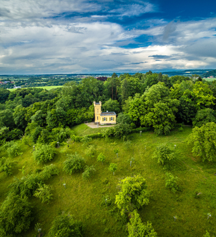 Eine kleine Villa mit Turm steht auf einem grünen Hügel, umgeben von grünen Bäumen. | © Stadtverwaltung Crailsheim