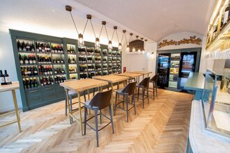In der Vinothek gibt es Tische und Stühle, an der Wand stehen große Flaschenregale | © Touristikgemeinschaft Hohenlohe e. V.  | Hotel Anne-Sophie