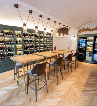 In der Vinothek gibt es Tische und Stühle, an der Wand stehen große Flaschenregale | © Touristikgemeinschaft Hohenlohe e. V.  | Hotel Anne-Sophie