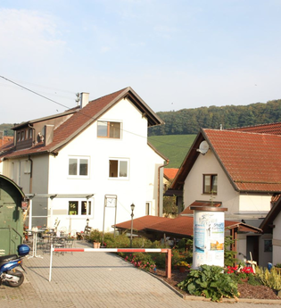 Die Ferienwohnung liegt in einem Haus am Ortsrand, davor befindet sich der Eisenbahnwaggon | © Touristikgemeinschaft Hohenlohe e. V.