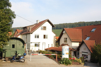 Die Ferienwohnung liegt in einem Haus am Ortsrand, davor befindet sich der Eisenbahnwaggon | © Touristikgemeinschaft Hohenlohe e. V.