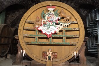 Im Museum steht ein großes altes Weinfass, davor sind Kerzen angezündet | © Touristikgemeinschaft Hohenlohe e. V. | Marion Schlund