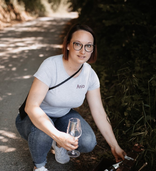 Die Weinerlebnisführerin kniet auf einem Weg und holt eine Flasche Wein aus einer Kiste | © Touristikgemeinschaft Hohenlohe e. V. | Anja Herterich