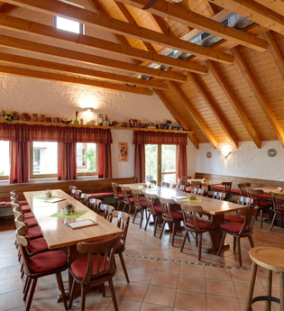 Die Besenwirtschaft ist rustikal mit Tischen und Stühlen eingerichtet. Die Decke hat helle Balken. | © Touristikgemeinschaft Hohenlohe e. V.