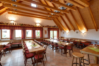 Die Besenwirtschaft ist rustikal mit Tischen und Stühlen eingerichtet. Die Decke hat helle Balken. | © Touristikgemeinschaft Hohenlohe e. V.