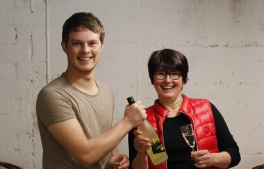 Susanne und Gerrit Schmezer halten zwei Flaschen Wein in den Händen | © Touristikgemeinschaft Hohenlohe e. V. |  Weingut Gaufer
