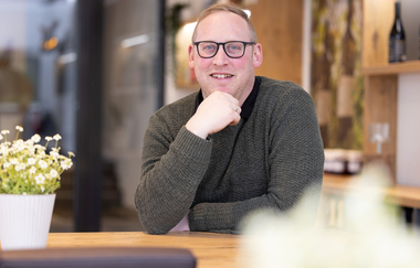 Lucas Schwab sitzt in der Vinothek des Weingutes Heinz J. Schwab | © Touristikgemeinschaft Hohenlohe e. V. | Weingut Heinz J. Schwab