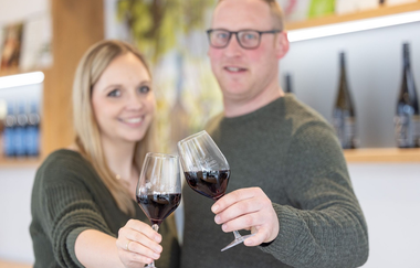 Weingut Heinz J. Schwab, ein Mann und eine Frau stoßen mit einem Glas Rotwein an | © Touristikgemeinschaft Hohenlohe e. V. | Weingut Heinz J. Schwab