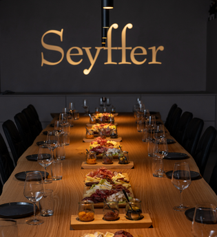 Tagungsraum mit goldenem Schriftzug an Wand "Seyffer", lange Holztafel, eingedeckt mit Essen in der Mitte | © Christian Seyffer