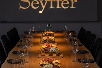 Tagungsraum mit goldenem Schriftzug an Wand "Seyffer", lange Holztafel, eingedeckt mit Essen in der Mitte | © Christian Seyffer