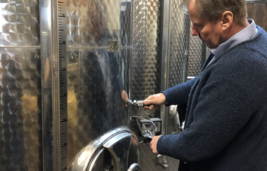 Der Winzer kontrolliert den Wein am Edelstahltank im Weinkeller | © Touristikgemeinschaft Hohenlohe e.V.| Weingut Ungerer