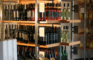 Regale mit Wein und regionalen Produkten stehen zum Verkauf bereit und davor liegen Weine in einem Korb mit Glas bereit für die Weinprobe | © Touristikgemeinschaft Hohenlohe e.V. | Weingut Ungerer