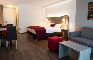 Hotelzimmer mit Doppelbett, Couch und kleiner Essecke | © Touristikgemeinschaft Hohenlohe e. V.