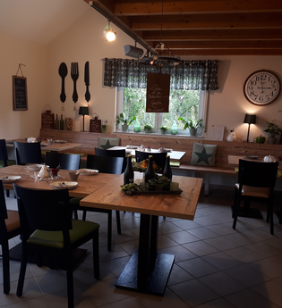 Weinstube mit Sitzgelegenheiten zum Essen, urige Dekoration an den Wänden und großer Uhr neben einem Fenster | © Weinlodge am Geisberg