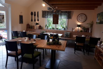 Weinstube mit Sitzgelegenheiten zum Essen, urige Dekoration an den Wänden und großer Uhr neben einem Fenster | © Weinlodge am Geisberg