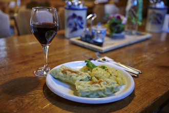 Ein Teller mit Maultaschen und Kartoffelsalat neben einem Glas Rotwein auf einem Holztisch in einer gemütlichen Besenwirtschaft | © Kraichgau-Stromberg Tourismus e.V.