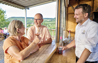 Ein Pärchen steht an der Weinausgabe am Wengertshäusle und prostet sich zu. | © Touristikgemeinschaft HeilbronnerLand