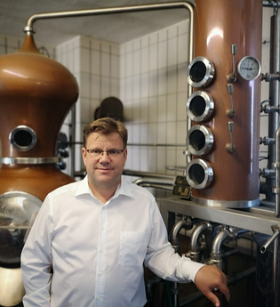 Fritz Lösch vor dem Brenngerät | © Touristikgemeinschaft Hohenlohe e. V. | Winzerstube Lösch