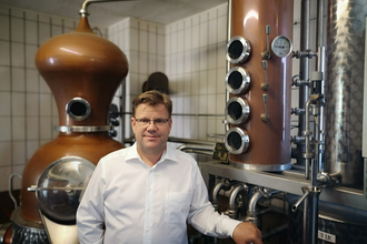 Fritz Lösch vor dem Brenngerät | © Touristikgemeinschaft Hohenlohe e. V. | Winzerstube Lösch