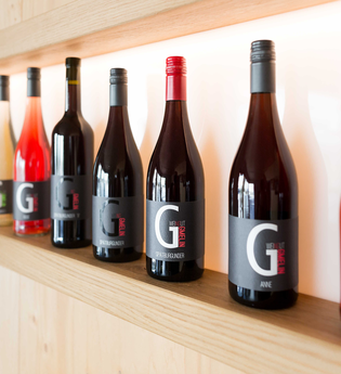 Verschiedene Weinflaschen des Weingut Gmelin auf einem Holzregal