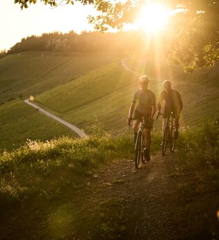 Mann und Frau gravelbiken über die Höhenzüge des Kraichgau-Strombergs. Im Hintergrund Sonnenuntergang. | © Tourimia Tourismus GmbH | Stefan Leitner Photography