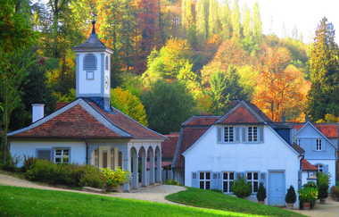 Die Kapelle und Gebäude des Fürstenlagers mit einer gepflegten Rasenfläche im Vordergrund und bunt gefärben Bäumen im Hintergrund. | © Maria Zimmermann