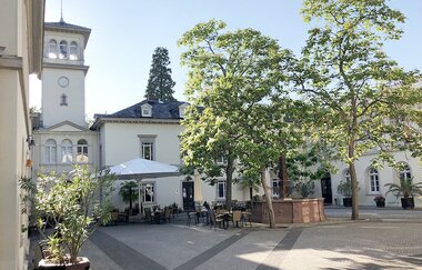 Ein schöner Innenhof mit Bäumen und Sitzmöglichkeiten von Gebäuden umgeben. | © Bettina Gessinger