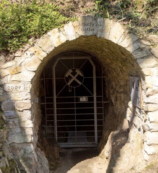 Steinernes Tor mit Gitter und der Aufschrift "Hülfe Gottes" aus 2009 in bewachsenem Gelände. | © Roland Robra / Tourismus Service Bergstrasse Burgensteig