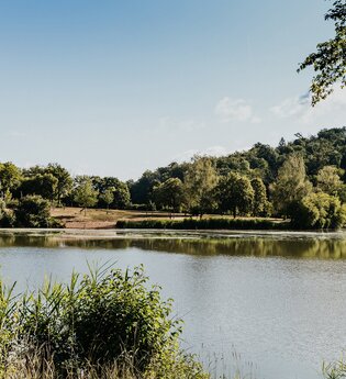 Blick auf den See, im Hintergrund ist Liegewiese und Sandstrand zu sehen