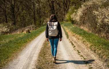 Eine Frau mit Rucksack wandert auf einem Weg in den Wald hinein. | © Stadtverwaltung Crailsheim