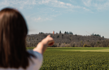 Eine Person zeigt mit dem Finger auf den Burgbergturm, einen Turm, der auf einem leicht erhöhten Berg liegt | © Stadtverwaltung Crailsheim
