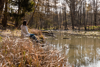 Eine Frau sitzt in einem See, der umrandet ist von Bäumen und Schilf | © Stadtverwaltung Crailsheim