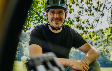 Ein Radfahrer sitzt auf einem Stein und lächelt in die Kamera | © Stadtverwaltung Crailsheim