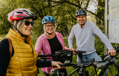 Zwei Radfahrerinnen und ein Radfahrer stehen vor einer Radinformationstafel und lächeln in die Kamera | © Stadtverwaltung Crailsheim