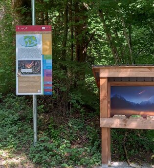 bunte Infotafel am Gaildorfer Geopfad, daneben Wurfbude mit Dinosauriern
