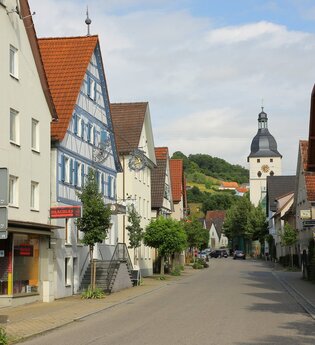 Entlang der Straße reihen sich Häuser und eine Kirche ist am Ende. | © Touristikgemeinschaft Hohenlohe e. V. | Andi Schmid