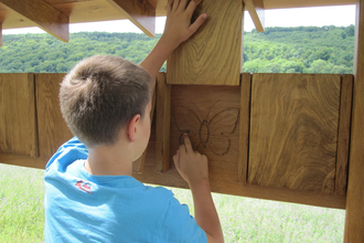 Ein Junge schaut, was sich einer Holztafel befindet | © Touristikgemeinschaft Hohenlohe e. V.  |  Gemeinde Dörzbach