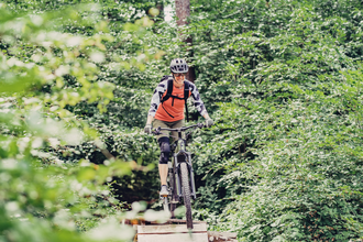 Eine Mountainbikerin fährt auf ihrem Bike auf einem Trail durch den Wald | © Touristikgemeinschaft Odenwald e.V.