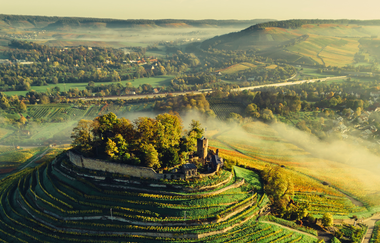Drohnenaufnahme der Burgruine Weibertreu im Morgennebel. Aussicht über Weinsberger Tal mit dem Naturpark Schwäbisch-Fränkischer Wald im Hintergrund. | © Touristikgemeinschaft HeilbronnerLand