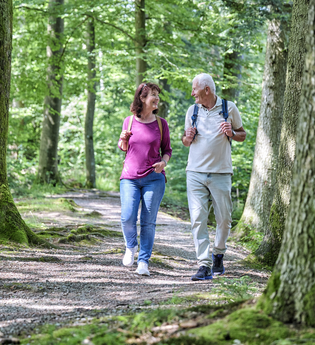 Ein Paar unternimmt eine Wanderung durch den Wald. Sie schauen sich an und lachen. | © Hohenlohe Schwäbisch Hall Tourismus e. V.
