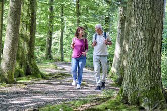 Ein Paar unternimmt eine Wanderung durch den Wald. Sie schauen sich an und lachen. | © Hohenlohe Schwäbisch Hall Tourismus e. V.